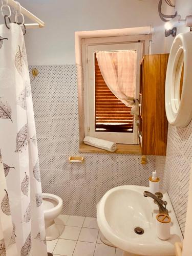 a bathroom with a sink and a toilet and a window at Alloggio nel Borgo Marinaro in Cittadella del Capo
