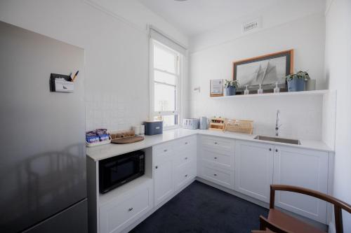 a kitchen with white cabinets and a sink and a window at Shipwrights Arms Hotel in Hobart