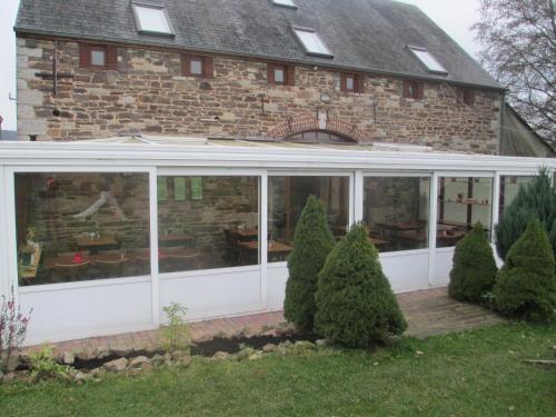 a conservatory with glass doors in front of a building at La Ferme de Werpin in Hotton