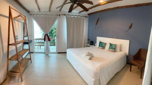 a bedroom with a white bed with a ceiling fan at Lodge Arenas Costa Maya in Mahahual