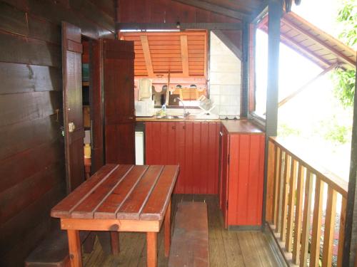 a small kitchen with a wooden bench on a balcony at Gîtes BB in Bouillante