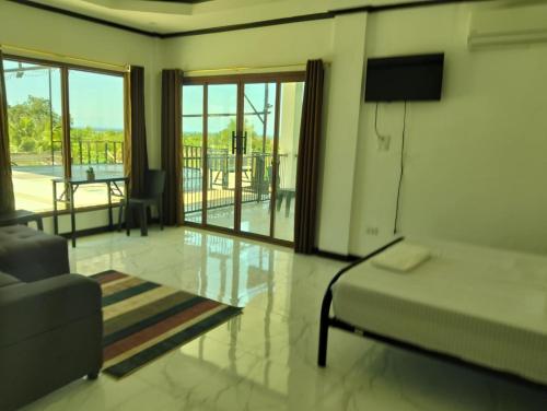 a bedroom with a bed and a couch and a television at Safe Haven Residence in Talibon