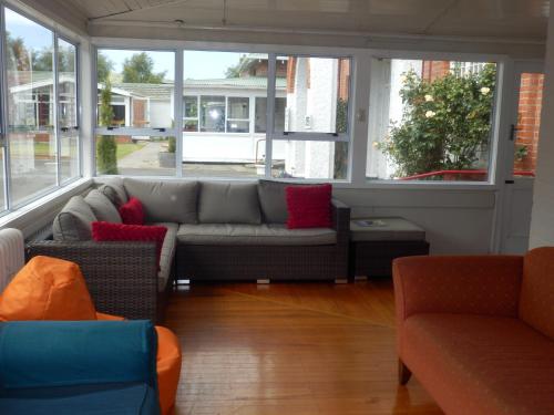 sala de estar con sofá gris y almohadas rojas en Thomas's Catlins Lodge and Camp Ground, en Owaka