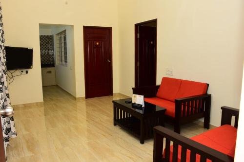 a living room with a red chair and a couch at Skandavanam in Tiruvallūr