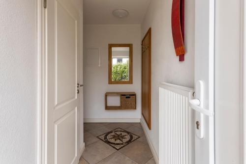 a hallway with a white door and a mirror at Haus im Halligweg 18 in Nordstrand