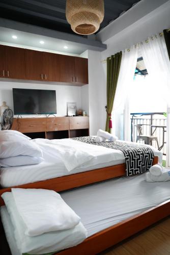 two beds in a bedroom with a tv at Mountain and Sunsetview Baguio Residences in Baguio