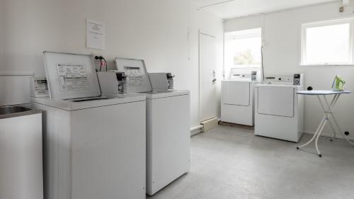 a laundry room with white appliances and a table at Heartland Hotel Glacier Country in Fox Glacier