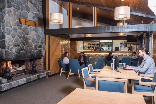 a fireplace in a restaurant with people sitting at tables at Heartland Hotel Glacier Country in Fox Glacier