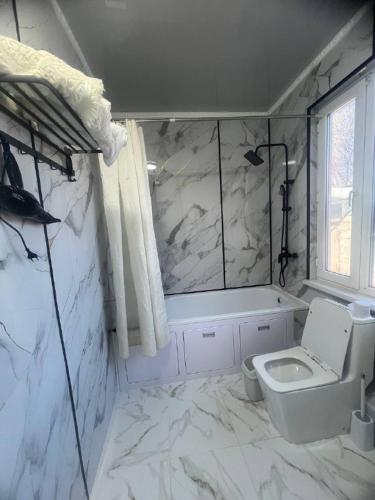 a white bathroom with a toilet and a bath tub at Adventure Guest House in Pokrovka