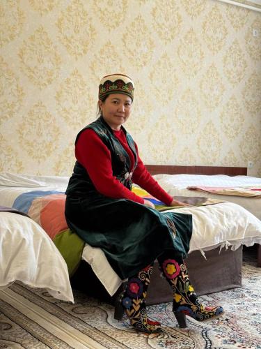a woman sitting on top of a bed at Adventure Guest House in Pokrovka