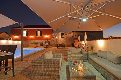 an outdoor patio with a couch and an umbrella at Islander house with pool in Trogir
