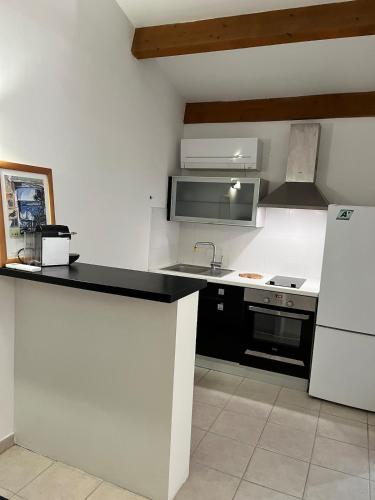 a kitchen with a black counter and a white refrigerator at Charming studio in a residence in Provence in Graveson