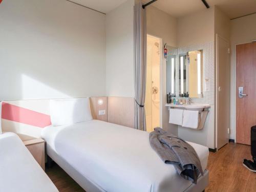 a bedroom with a large white bed and a bathroom at ibis budget Genève Petit-Lancy in Geneva