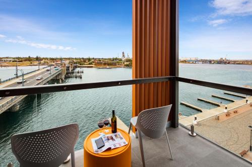 a table and chairs on a balcony with a view of the water at Quest Port Adelaide in Adelaide