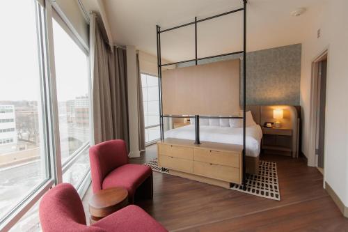 a bedroom with a canopy bed and two chairs at Hilton Garden Inn Sioux Falls Downtown in Sioux Falls