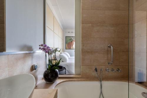 a bathroom with a bath tub and a mirror at DoubleTree by Hilton Florence Metropole in Florence