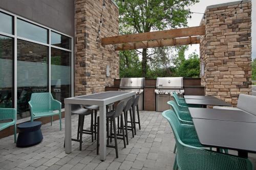 a patio with tables and chairs and an outdoor kitchen at Home2 Suites By Hilton Columbus Easton in Columbus