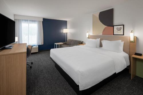 a hotel room with a large white bed and a television at Spark by Hilton Decatur in Decatur