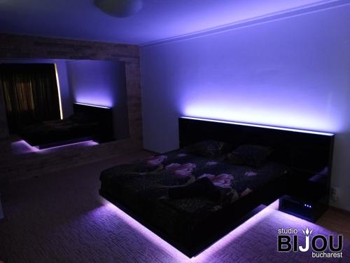 Habitación oscura con cama con luces moradas en Studio Bijou Bucharest, en Bucarest