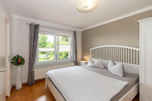 a bedroom with a white bed and a window at Bungalow Becker "Am Feldrand" in Jennewitz