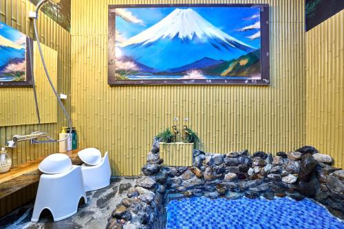a bathroom with a painting of a mountain on the wall at 新規オープン岩風呂付ゲストハウス織姫 in Fujiyoshida