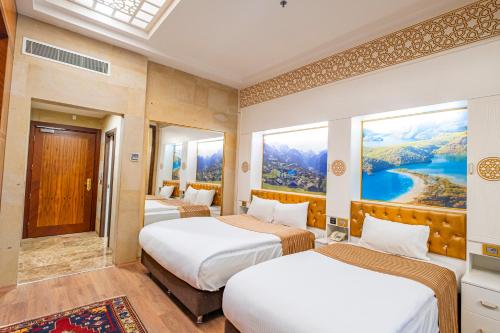 a hotel room with two beds and a painting on the wall at GHERDAN GOLD OTEL in Konya