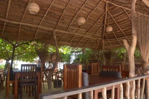 un restaurante con una mesa y sillas bajo un techo en Cinnabar Resort, en Tangalle