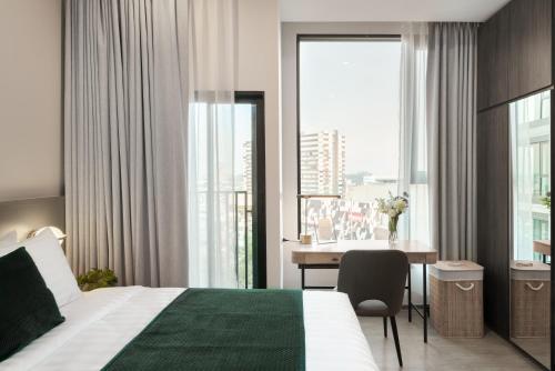 a hotel room with a bed and a desk and a window at Hampton Sriracha in Si Racha