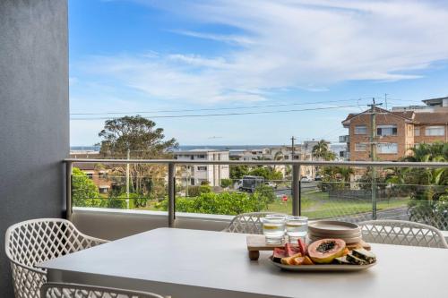 a table with a plate of food on a balcony at Salt & Sky - Stylish Apartment with Pool & Spa in Caloundra