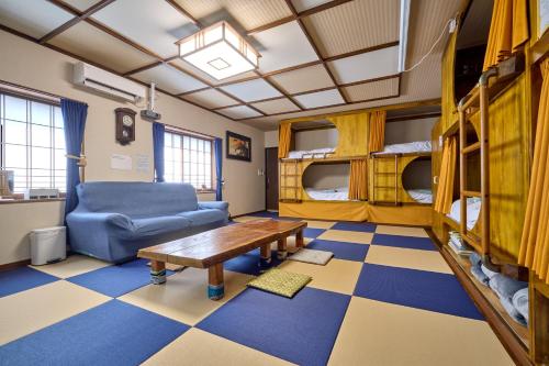 a living room with a couch and a table and bunk beds at 新規オープン岩風呂付ゲストハウス織姫 in Fujiyoshida
