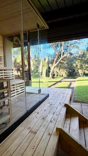 a wooden porch with a bench and a large window at MELLOW TREES Lake front studio with sauna in Budgewoi