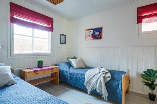 a bedroom with two beds and a table and window at Järven Helmi in Äkäslompolo