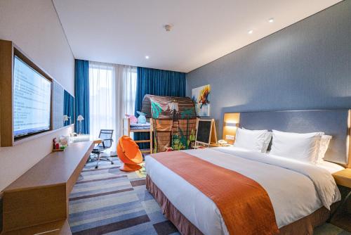 a hotel room with a bed and a flat screen tv at Holiday Inn Express Leshan City Square by IHG - High Speed Rail and Leshan Giant Buddha in Leshan