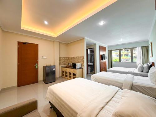 a hotel room with two beds and a television at Svarna Hotel in Sanur