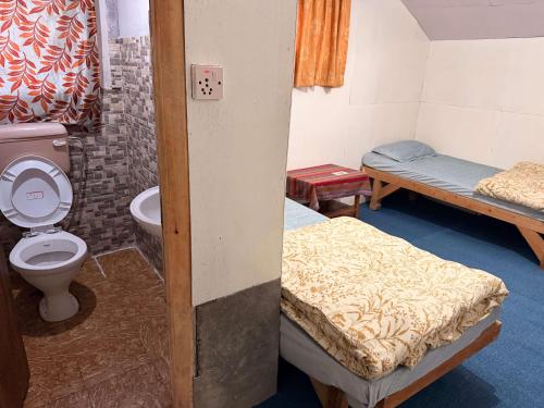 a room with two beds and a toilet and a sink at Phakding Camp One Lodge in Phakding