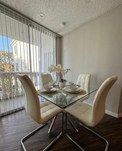 a dining room with a glass table and white chairs at Modern 2BR Hollywood Apt with Rooftop Pool, Free Parking & Close to Walk of Fame and Universal Studios in Los Angeles