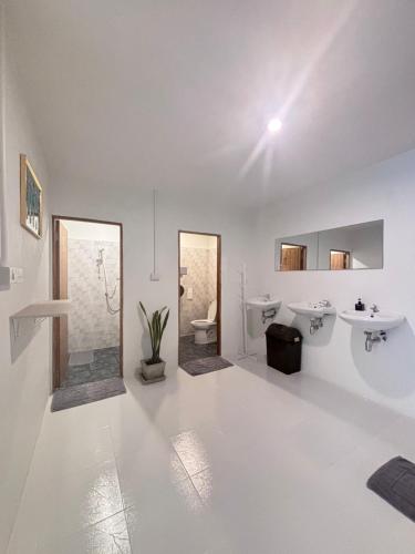 a white bathroom with two sinks and two mirrors at Bingo Hostel Khao Sok in Khao Sok National Park