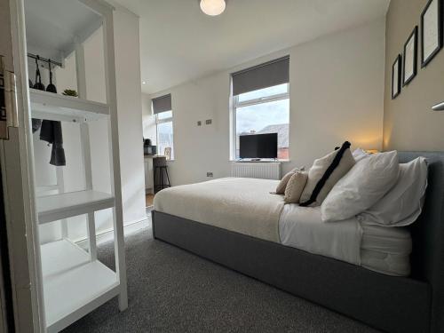 a white bedroom with a bed and a window at Camden St Accommodation in Derby