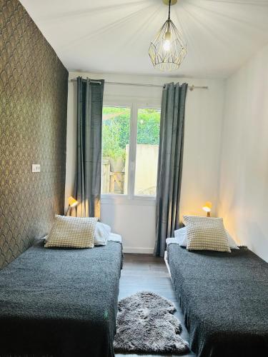 two beds in a room with a window at Appartement jardin in Le Cannet