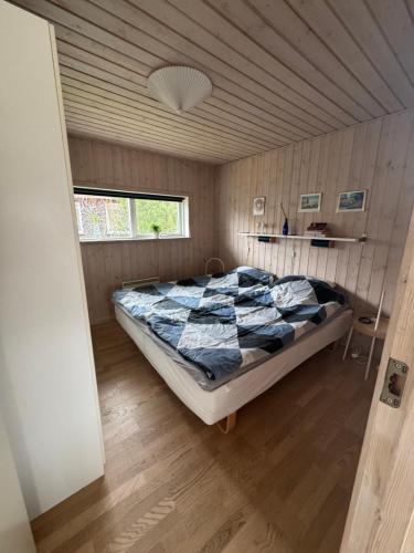 a bedroom with a large bed in a wooden room at Marielyst feriehus in Bøtø By