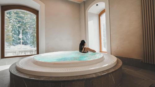a woman sitting in a hot tub in a room at TH Borca di Cadore - Park Hotel Des Dolomites in Borca di Cadore