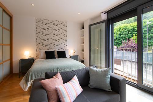 a bedroom with a bed and a couch next to a window at Loft Ladeira Real in Baiona