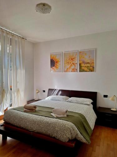 a bedroom with a bed with three paintings on the wall at Apartment near Lake Como -300m to station -AC in Valmadrera