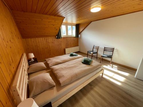 a bedroom with a large bed and two chairs at Gemütliche 3,5 Zimmer Wohnung in Unterseen