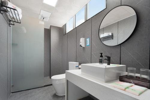 a bathroom with a white sink and a mirror at 花祺巨幕影院酒店 儋州那大镇夏日广场汽车站店 in Danzhou
