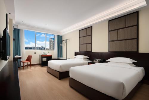 a hotel room with two beds and a desk at 花祺巨幕影院酒店 儋州那大镇夏日广场汽车站店 in Danzhou