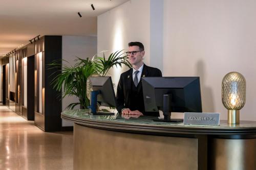 a man standing at a counter in a lobby at Rosa Grand Milano - Starhotels Collezione in Milan