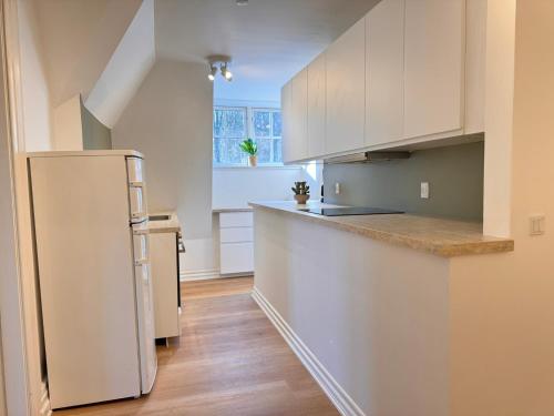 a kitchen with white cabinets and a refrigerator at aday - Aalborg Mansion - 3 bedroom apartment in Aalborg