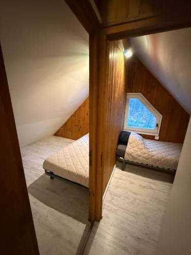 an attic room with two beds and a window at LK gîte la forêt in Chénérailles