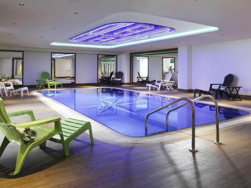 a pool in a hotel with a green chair and a bench at Ibis Styles Dubai Jumeira in Dubai